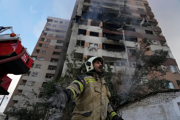 A-firefighter-calls-out-to-his-colleagues-at-the-scene-of-an-explosion-in-a-residential-compound-in-northern-Tehran-Iran-on-June-13-2025